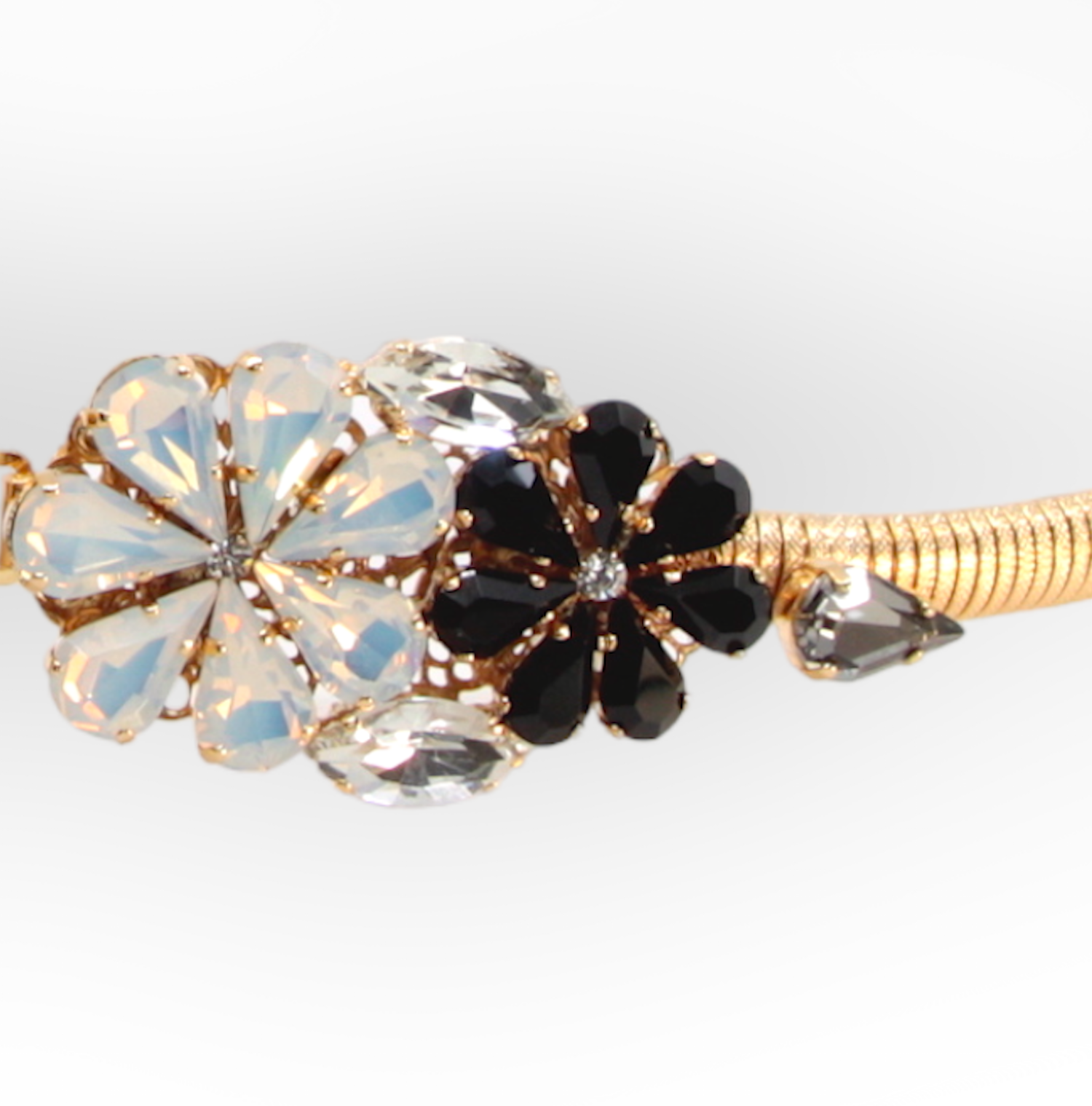 CINTURA IN METALLO ELASTICIZZATO PLACCATO ORO CON FIBBIA IN CRISTALLO A MAZZO DI MARGHERITE, NERA E BIANCA
