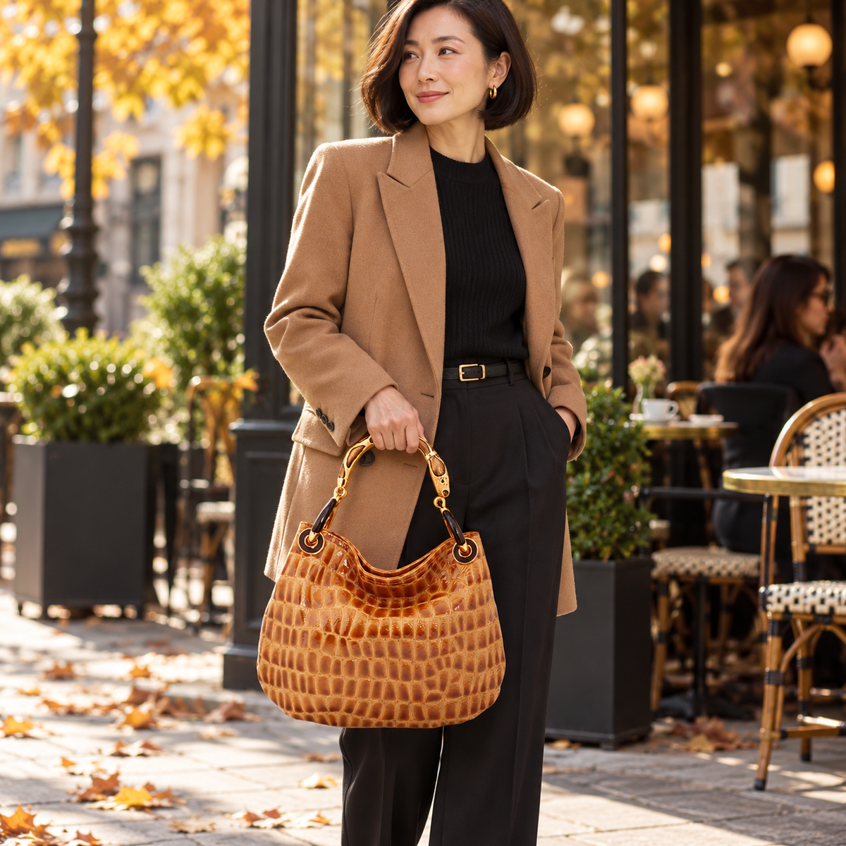 Woman carrying the INGA tan croco-embossed leather medium handbag with snake sculpture handle, styled for autumn.